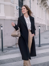 a lady wears a black trench coat with beige  pants